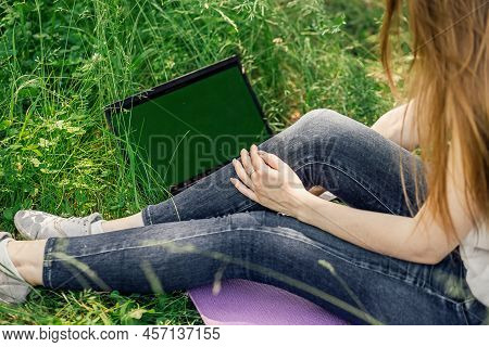 Girl Sits On The Grass And Works At A Laptop. Freelance. Selfeducation. The Concept Of Distance Lear