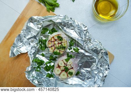 Two Garlic Heads On Foil With Oil And Herbs. Preparation Of Garlic For Baking. Preparation Of Garlic