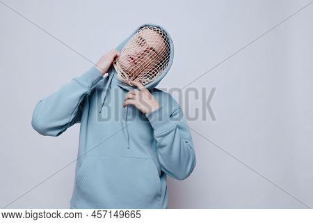 Tortured, Suffering From Problems, A Man With A Mesh On His Face Stands In A Light Blue Hoodie On A 