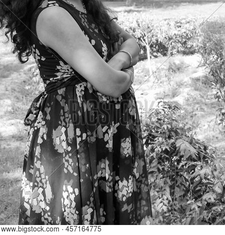 Indian Couple Posing For Maternity Baby Shoot. The Couple Is Posing In A Lawn With Green Grass And T