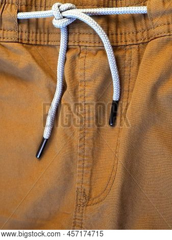 Khaki Men's Shorts With White Drawstring. Fragment With Codpiece. Textile Background. Vertical Image