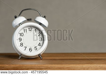 Alarm Clock Without Arrows. White Classic Alarm Clock On A Wooden Background Without Hands, Space To
