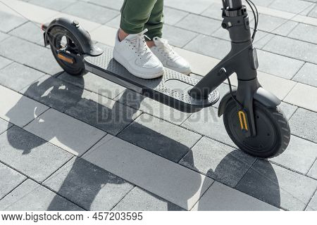 Woman In White Sneakers Is Standing On Electric Scooter