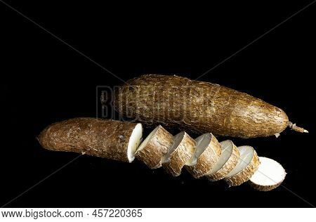 One Whole Yucca And One Cut Into Slices On Black Background