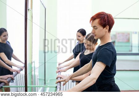Ballet Dancers Stands Near The Ballet Barre At The Ballet Hall. Warming, Training, Dancing In A Big 