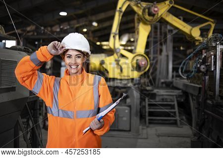 Portrait Of Smiling Female Supervisor Engineer Standing In Front Of An Industrial Robot Machine In F