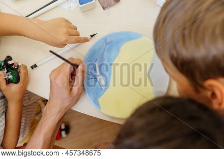 Children And Their Parents At A Clay Modeling Master Class Are Engaged In Painting A Newly Made Plat
