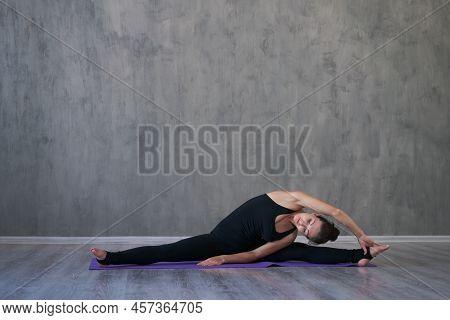 Athletic Young Woman Doing Yoga Isolated On Gray Wall Background In Black Sportswear Concept Of Heal