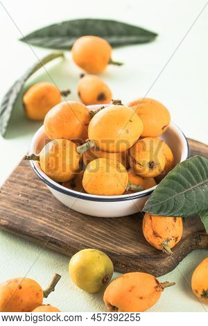 Ripe Medlar Fruit , Eriobotrya Japonica, And Green Medlar Leaves On Wooden Table. Top View