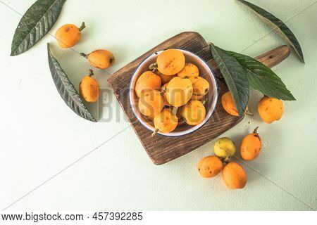 Ripe Medlar Fruit , Eriobotrya Japonica, And Green Medlar Leaves On Wooden Table. Top View