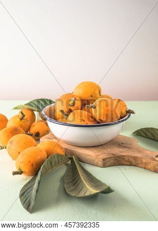 Ripe Medlar Fruit , Eriobotrya Japonica, And Green Medlar Leaves On Wooden Table. Top View