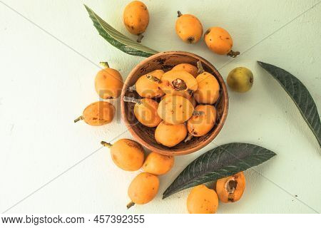 Ripe Medlar Fruit , Eriobotrya Japonica, And Green Medlar Leaves On Wooden Table. Top View