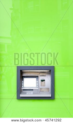 Atm Machine In Green Wall Shining In Sun.