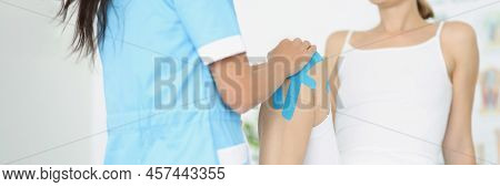 Close-up Of Female Patient Bend Knee, Woman Athlete With Kinesiotape, Blue Muscle Tape. Professional