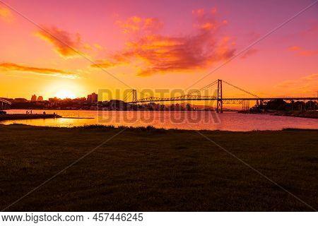 Hercilio Luz Cable Bridge With Bright Sunset And Reflection On Water In Florianopolis, Brazil