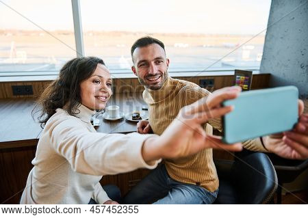 Beautiful Multi-ethnic Couple In Love Holding Smartphone In Outstretched Hands And Taking Self-portr