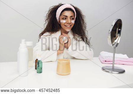 Lovely Tanned Pretty Curly Latin Lady Admiring Herself In Mirror Use Facial Cream Doing Beauty Proce