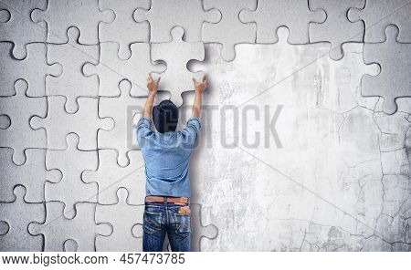 Man Making A Puzzle On The Wall.  Empty Wall With Space For Text
