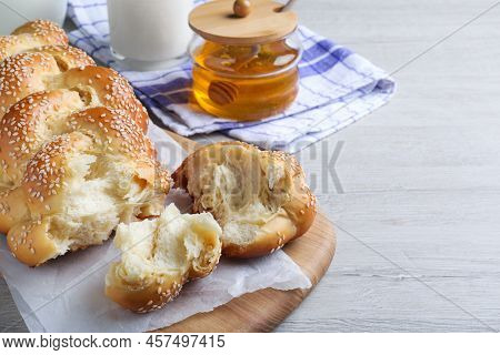 Broken Homemade Braided Bread With Sesame Seeds On Wooden Table, Space For Text. Traditional Shabbat