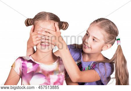 Children Play And Joke. One Girl Closes The Eyes Of Another. Photo Isolated On White Background