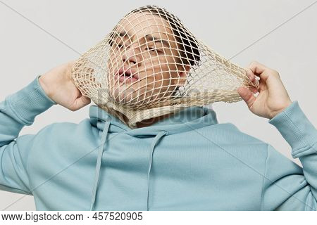 Tortured, Suffering From Problems, A Man With A Mesh On His Face Stands In A Light Blue Hoodie On A 
