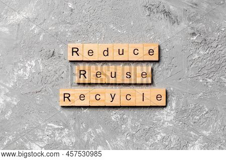 Reduce, Reuse And Recycle Word Written On Wood Block. Reduce, Reuse And Recycle Text On Cement Table