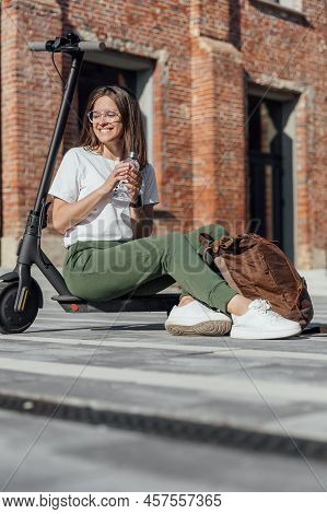 Woman In White Sneakers And Leather Backpack Sitting On Electric Scooter