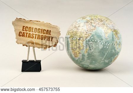 Ecological Concept. Near The Globe There Is A Clip With A Cardboard Plate On Which It Is Written - E