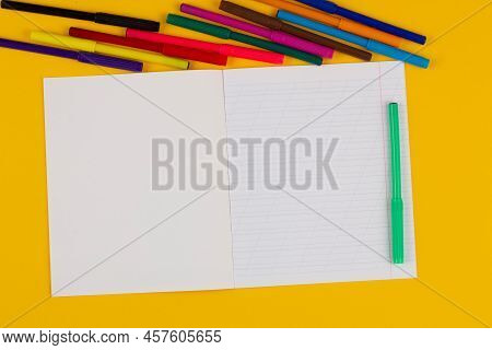 School Notebook On A Yellow Background With Copy Space For Text, Colorful Markers, English Alphabet.