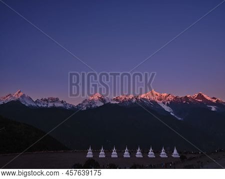 White Pagodas Of Feilai Temple With Meili Snow Mountain At Sunrise In Background In China's Yunnan P