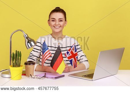 Positive Smiling Woman Holding Flags Of Usa, German And Great Britain, Bragging With Knowing Of Many