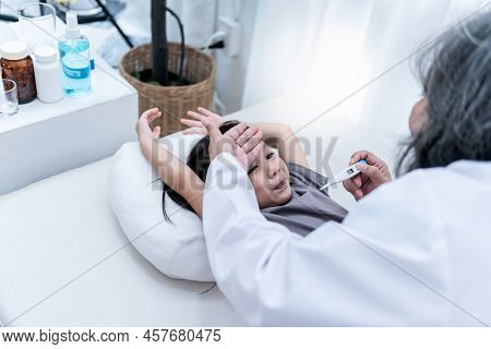 Woman Doctor Using Hand Touching The Forehead Of An Asian Girl Patient, To Check Body Temperature Fr