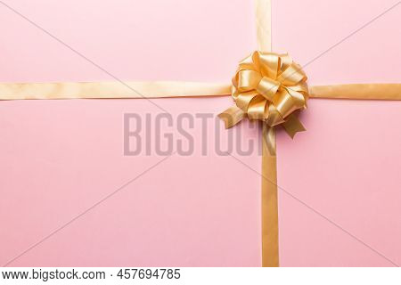 Top View Of Gold Ribbon Rolled And Yellowbow Isolated On Colored Background. Flat Lay With Copy Spac