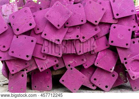 A Heap Of Support Material Steel Covering By Pink Rustproof Paint, On The Cocrete Floor In Front The