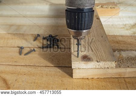 Screwing Screws Into Wooden Boards. Self-tapping Screws, A Screwdriver Drill And Wooden Boards. Home