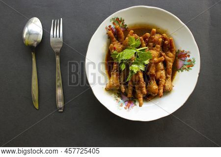 Spicy Chicken Feet With Celery, Chili, Onion, Garlic Served With A White Plate Isolated From A Black