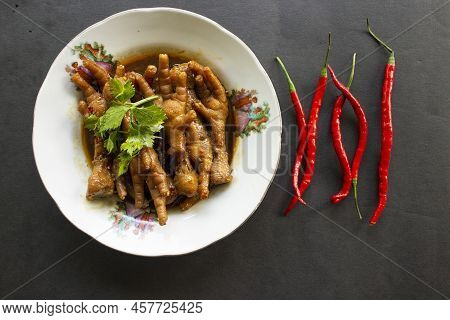 Spicy Chicken Feet With Celery, Chili, Onion, Garlic Served With A White Plate Isolated From A Black