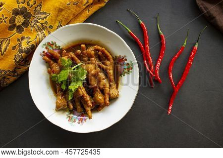 Spicy Chicken Feet With Celery, Chili, Onion, Garlic Served With A White Plate Isolated From A Black