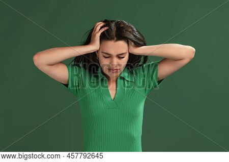 Portrait Of Beautiful Young Girl Posing, Holding Head, Suffering From Headache Isolated Over Green S