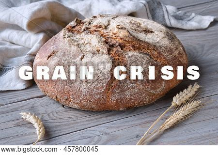 Text Grain Crysis On Background With Loaf Of Dark Bread On Wood With Linen Towel, Spelt Ears.