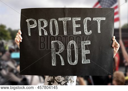A Womans Hands Hold A Protect Roe Banner. A Woman Stands Up For Her Rights With A Banner At A Rally.