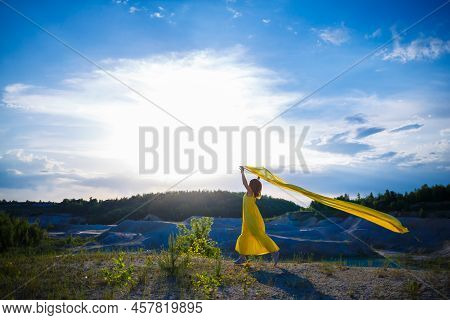 Happy Ukrainian Woman Running In Nature. In A Long Yellow Dress. Symbol Of Freedom Of Ukraine. Woman