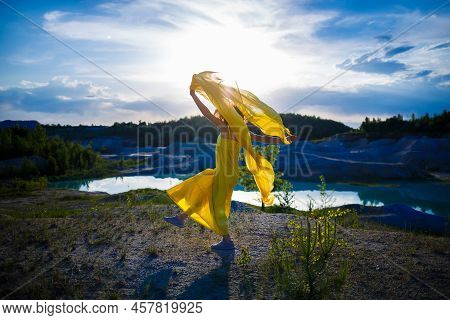 Happy Ukrainian Woman Running In Nature. In A Long Yellow Dress. Symbol Of Freedom Of Ukraine. Woman