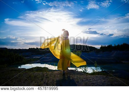 Happy Ukrainian Woman Running In Nature. In A Long Yellow Dress. Symbol Of Freedom Of Ukraine. Woman