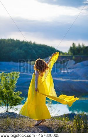 Happy Ukrainian Woman Running In Nature. In A Long Yellow Dress. Symbol Of Freedom Of Ukraine. Woman