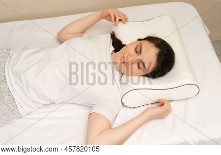 A Woman Sleeps On An Orthopedic Pillow Made Of Memory Foam, Lying On A Bed. The Correct Pillow For A