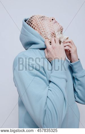 Tortured, Suffering From Problems, A Man With A Mesh On His Face Stands In A Light Blue Hoodie On A 