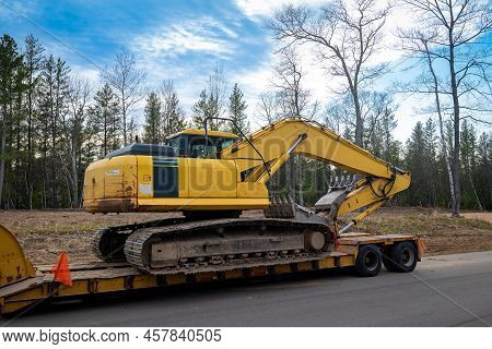Used Yellow Skid Steer Excavator Loader On A Flat Bed Trailer.