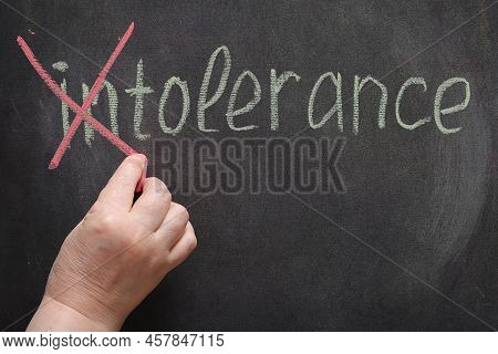 On The Black Board In White Chalk Is Written The Word Intolerance Female Hand Corrects The Word In R