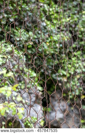 Natural Rock With Mesh To Protect Against Landslides Dangerously Sliding Down The Cliff Onto The Roa